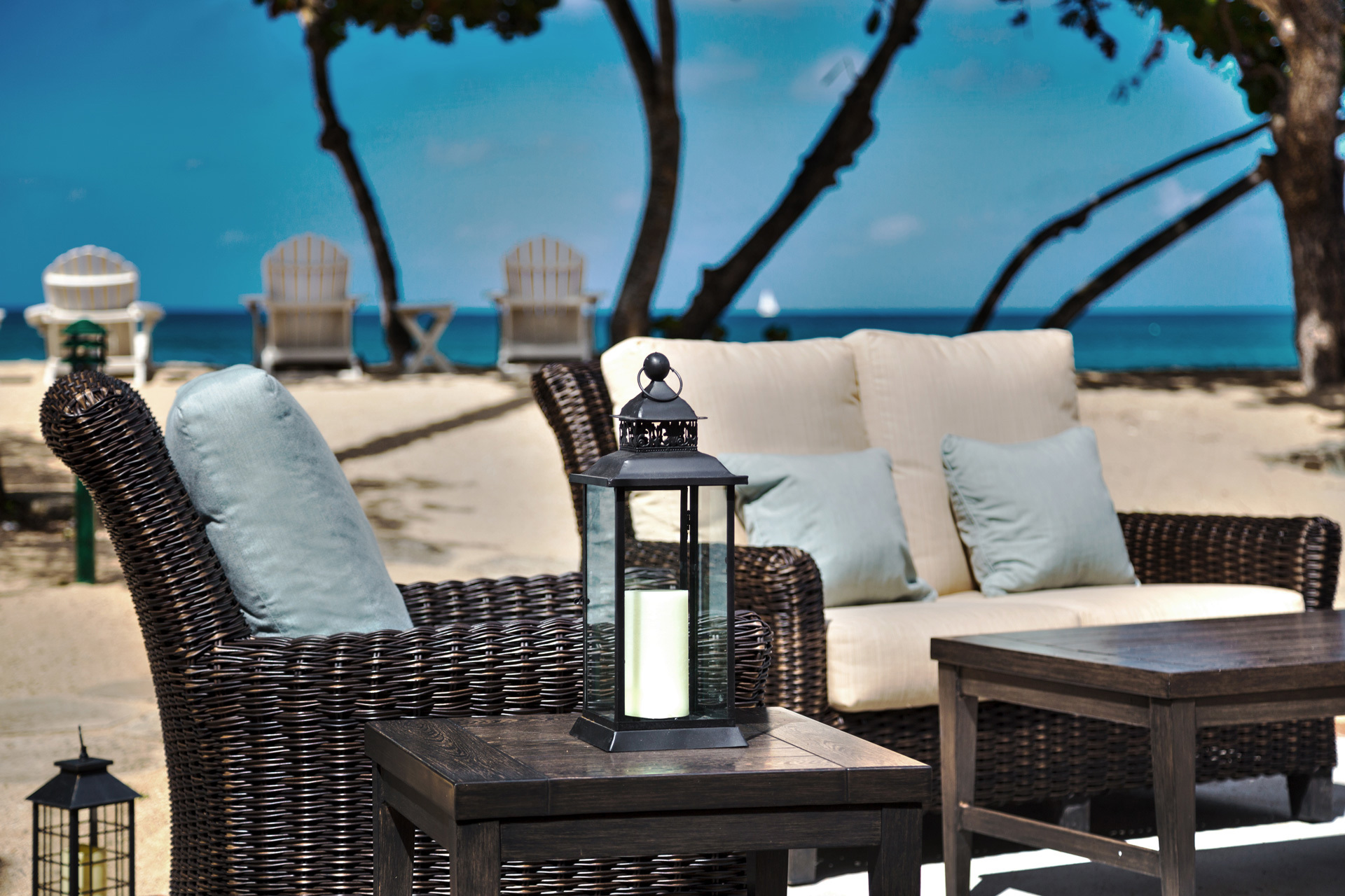 Black outdoor seating with light coloured pillows on a beach