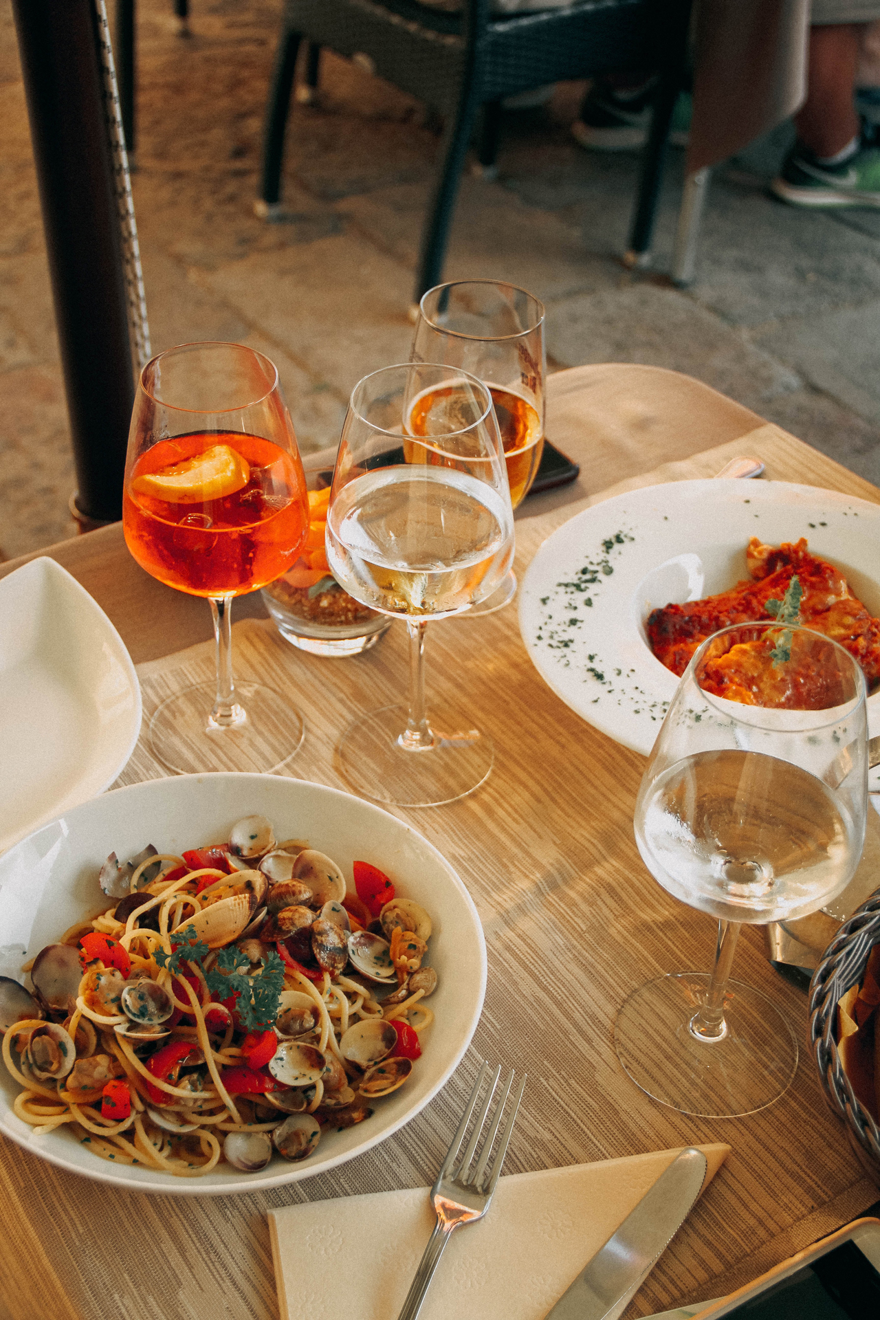 Two plates off food and four glasses of wine on a table