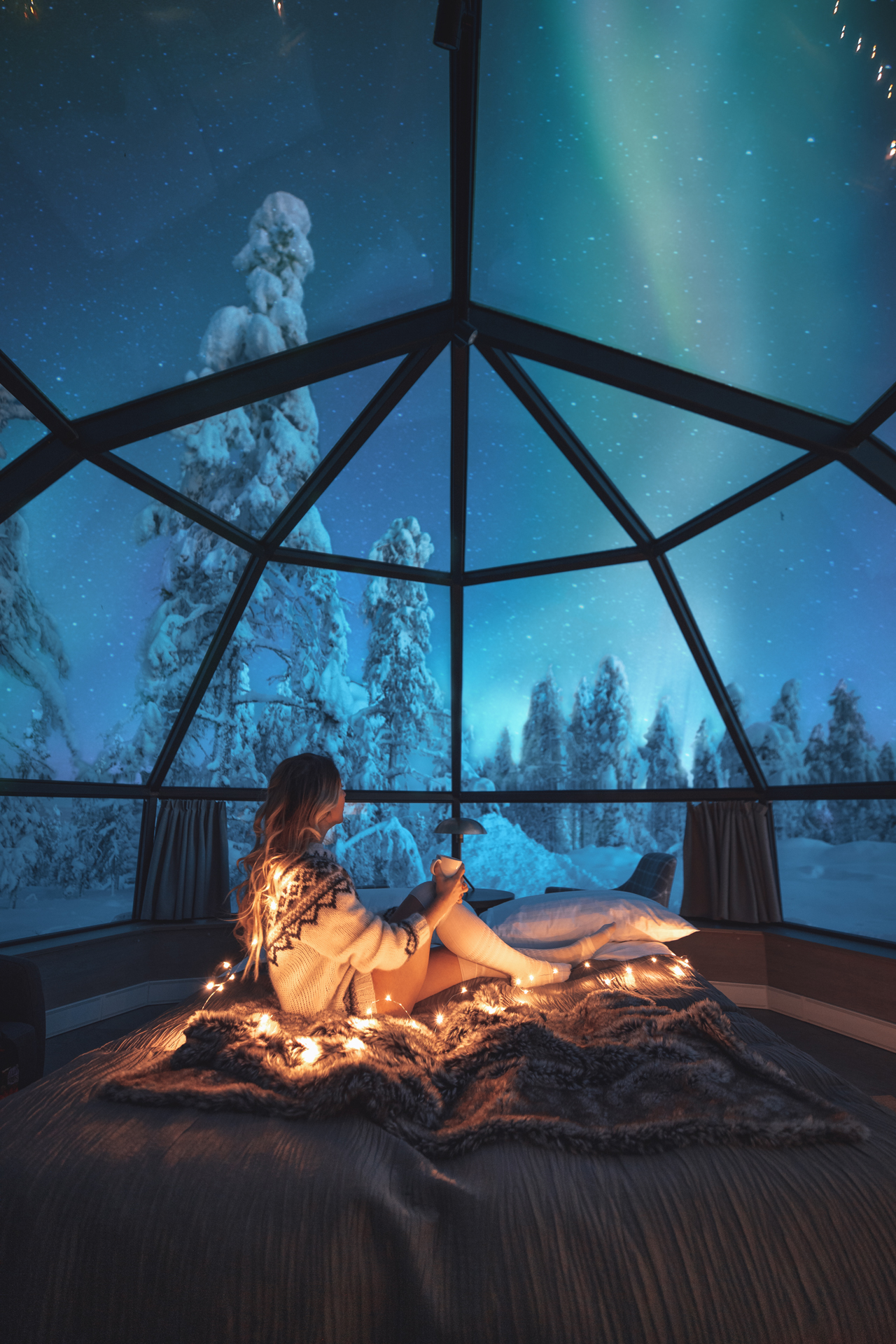 Young woman enjoying a view of the northern lights from a glass igloo