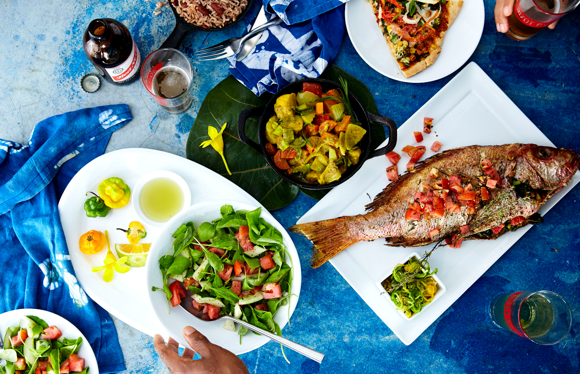 Fish and vegetables on a blue table with drinks