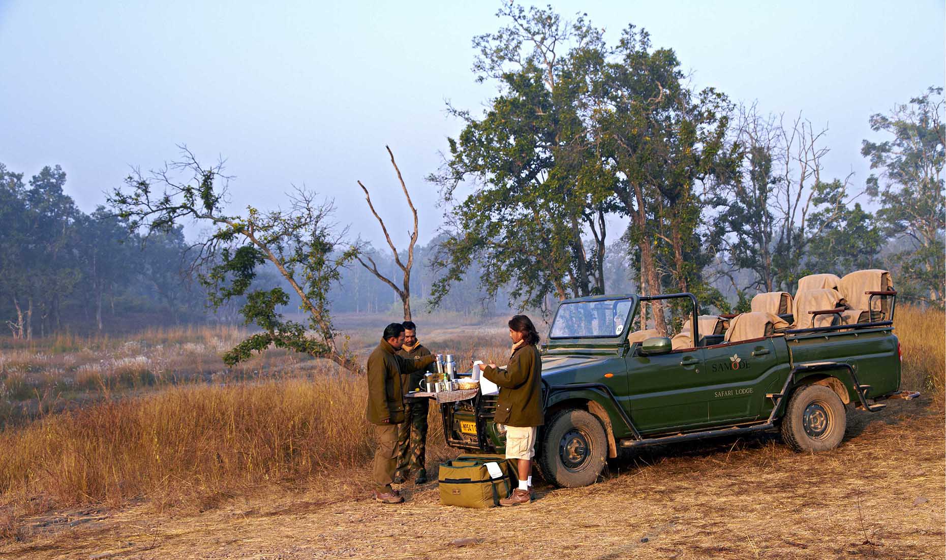 Asia, India, Samode Safari Lodge, three people having making hot drinks on the bonnet of a game drive vehicle