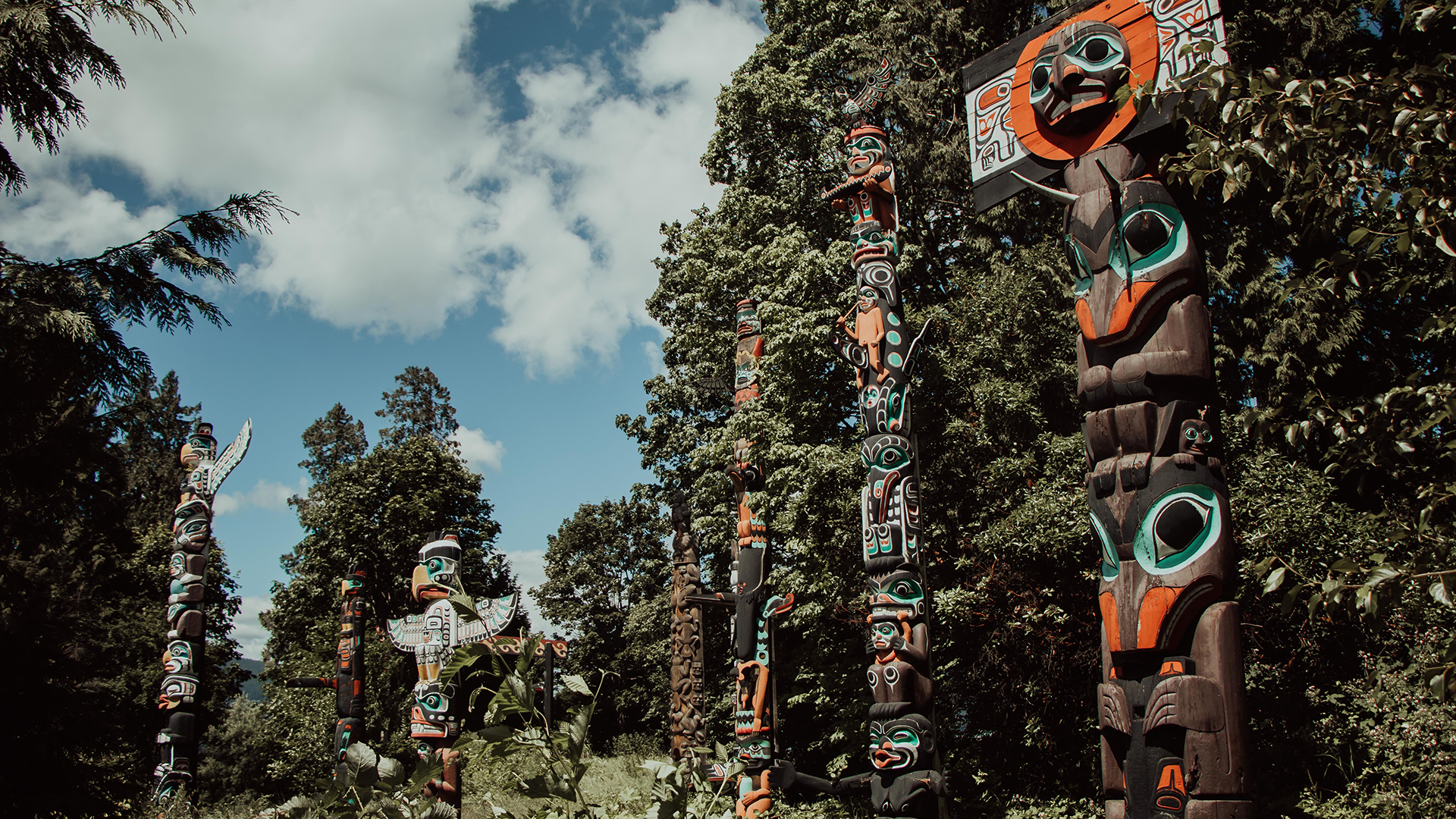 Colourful totem poles in front of trees in Vancouver, Canada