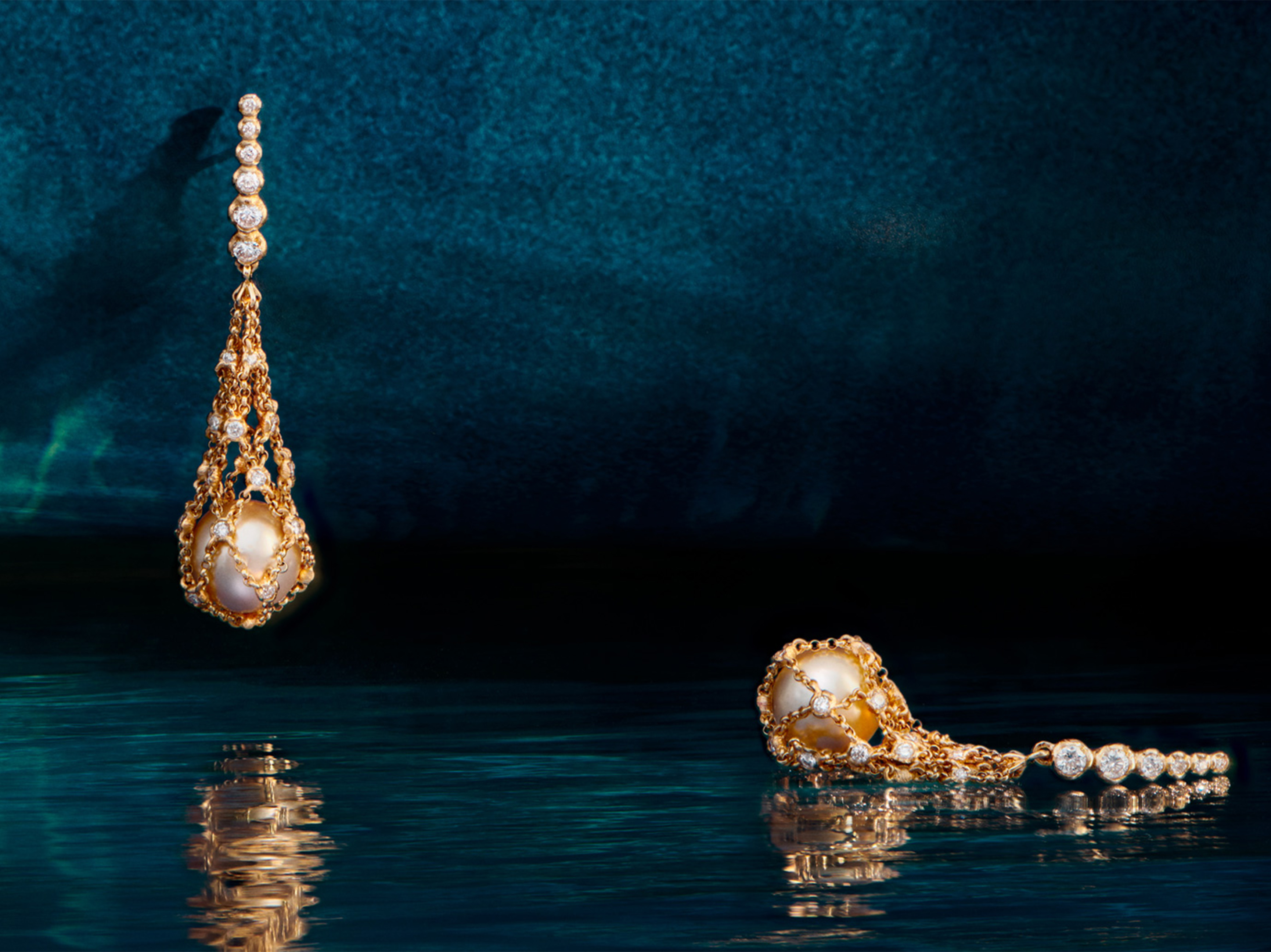 Yellow gold and pearl necklaces against a dark blue watery backdrop