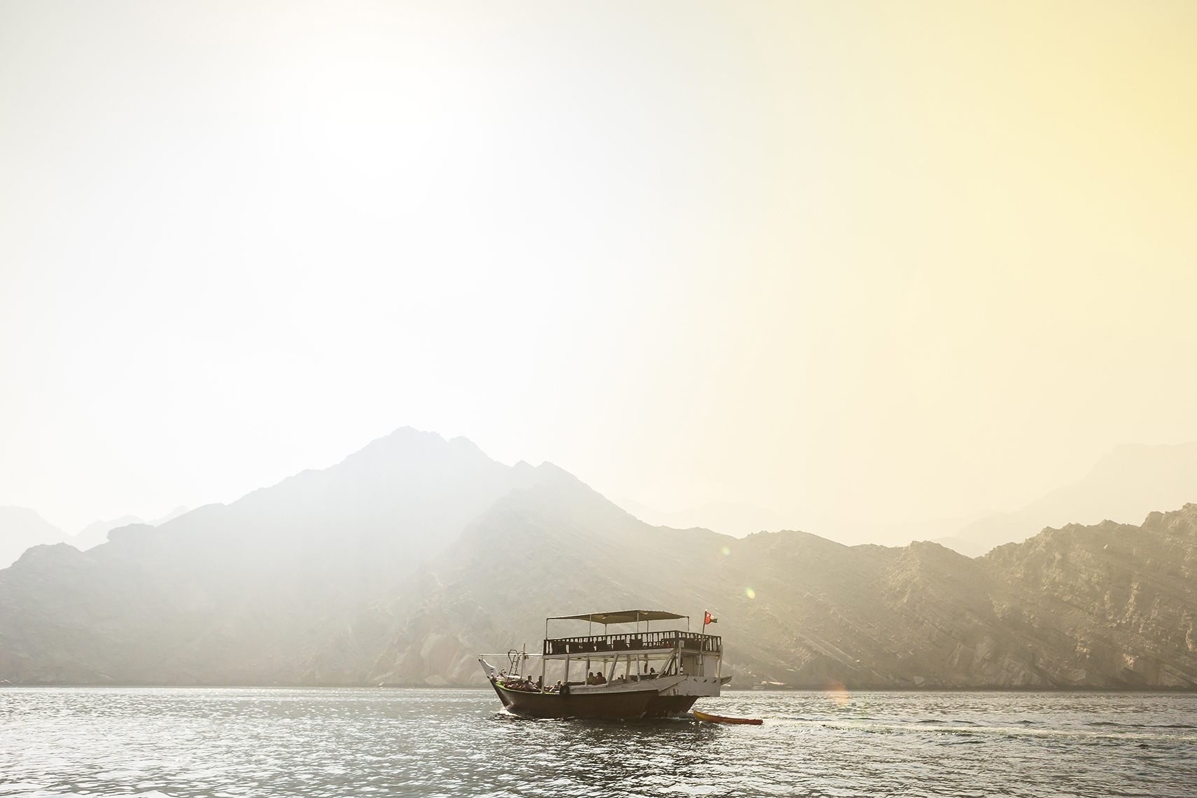 Traditional boat on the water in the Gulf of Oman backdropped by mountains