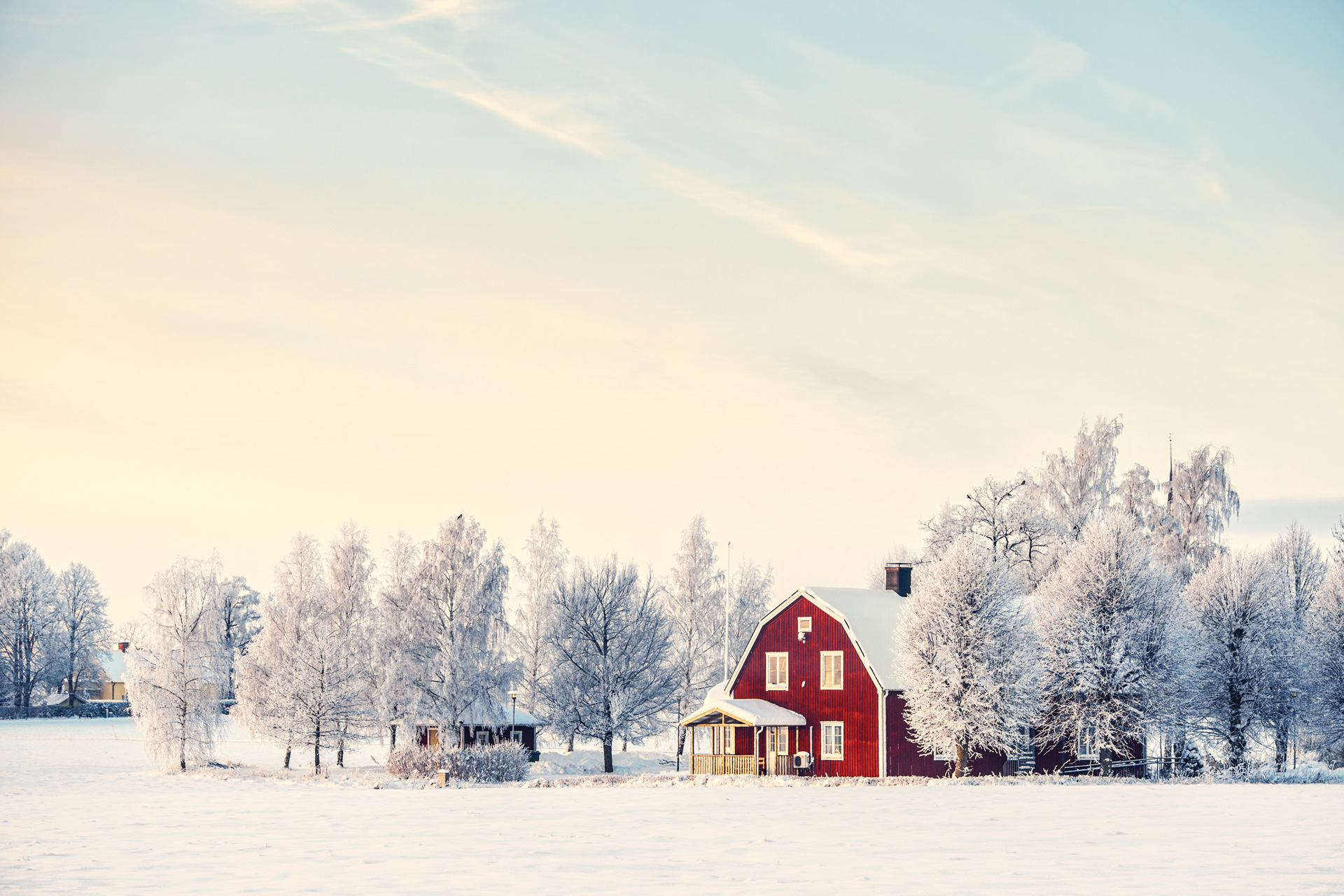 Red winter barn in between snowy trees