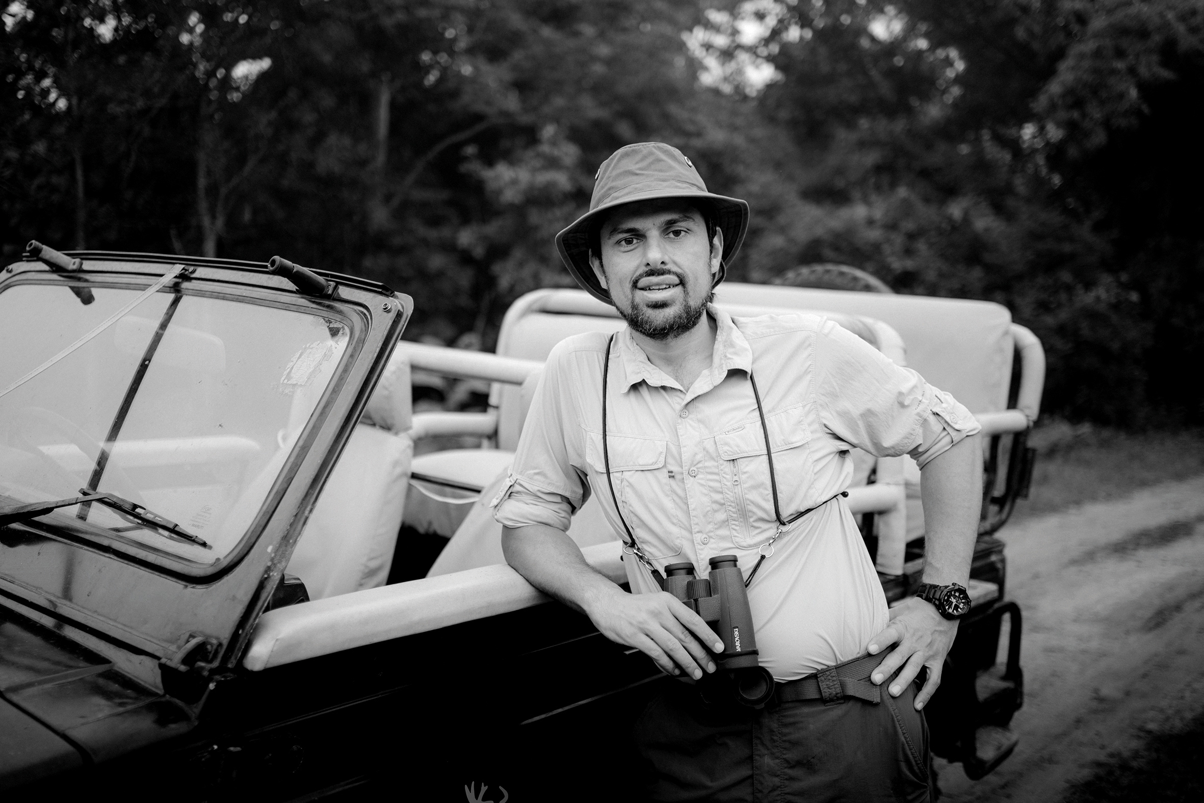 Aly Rashid the owner of Bori Safari Lodge leading against a keep with binoculars in hand in black and white