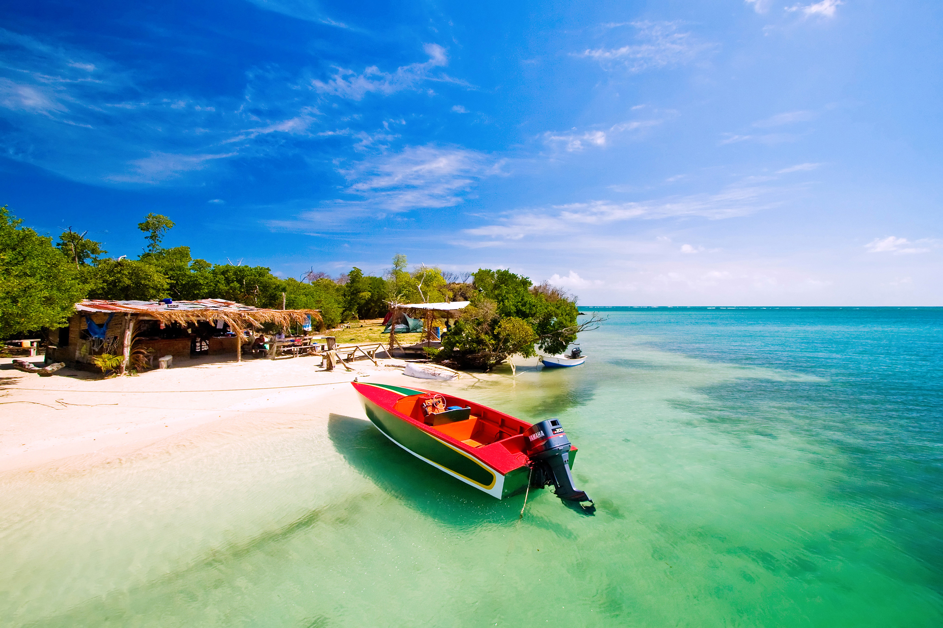 A red small boat with a motor sitting on a beach in Grenada