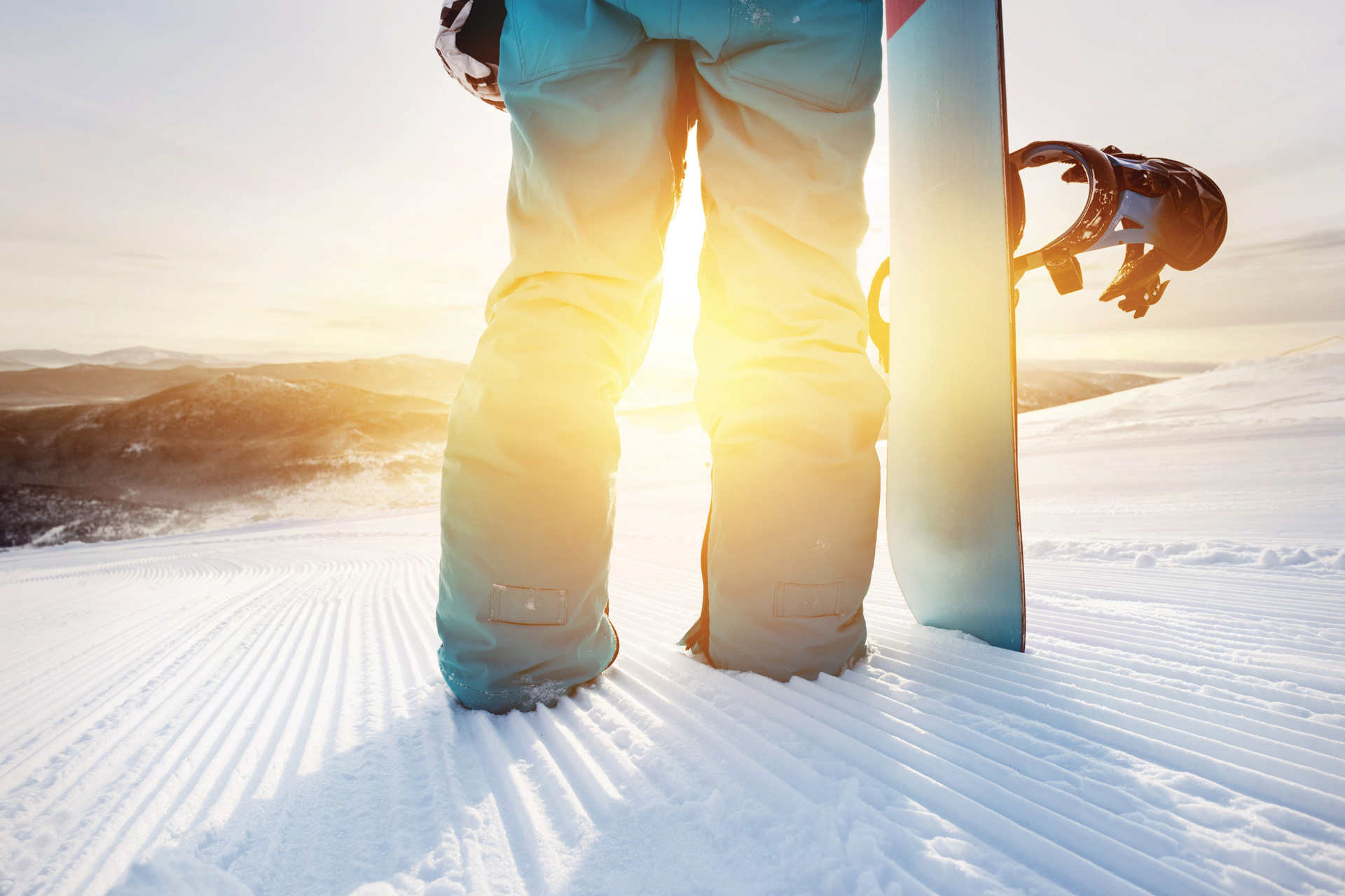 Closeup of a person on a ski slope holding a snowboard