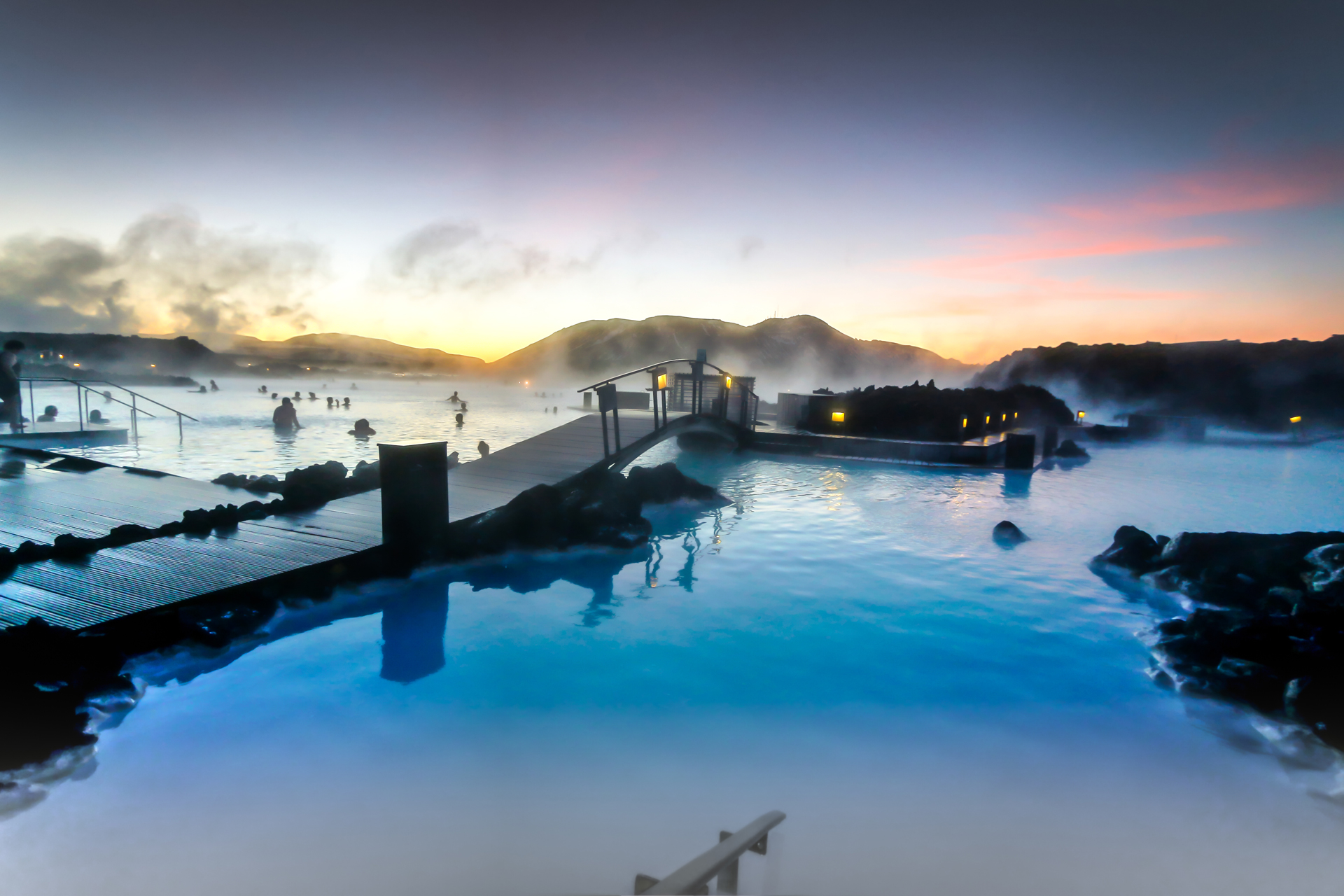 People in a steamy lagoon in Iceland as the sun sets