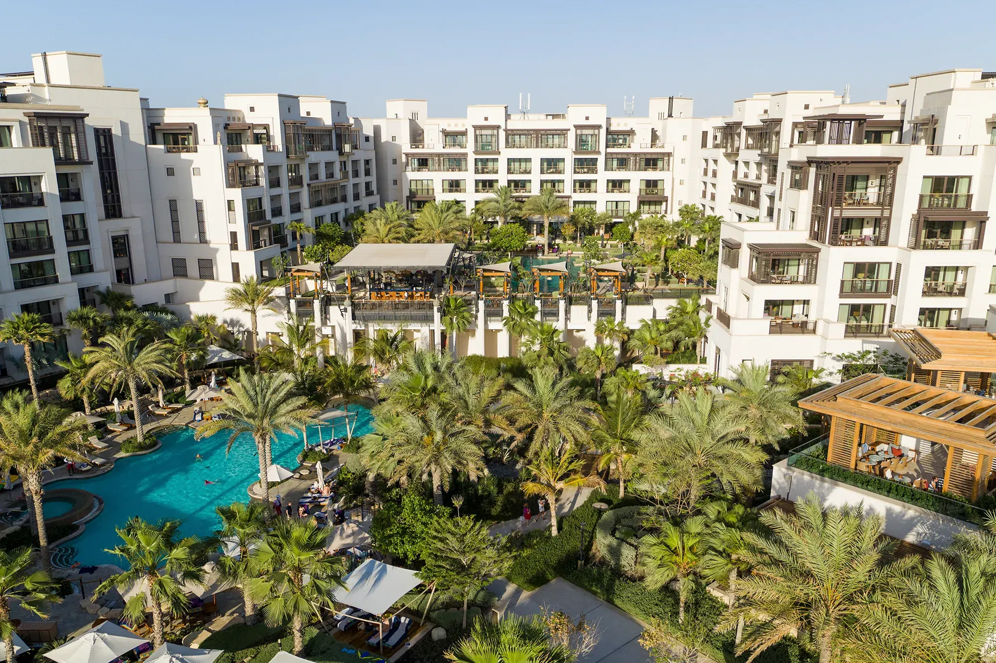 Aerial view of Jumeirah Al Naseem Dubai showcasing its palm‑lined pools, lush gardens and modern beachfront resort architecture.