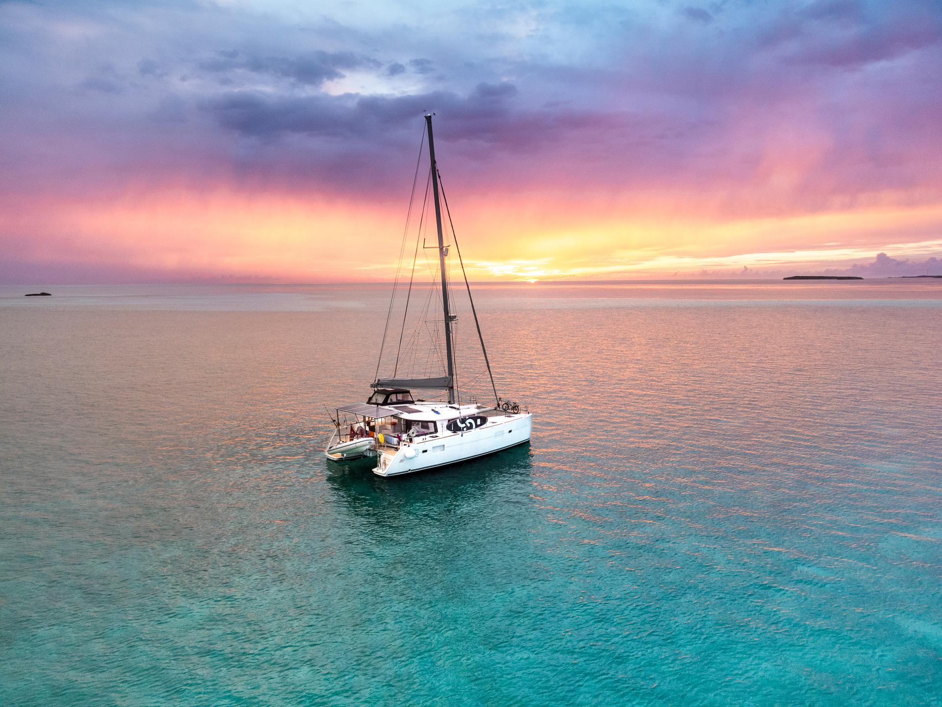 A small yacht on the sea with the sun setting in the background