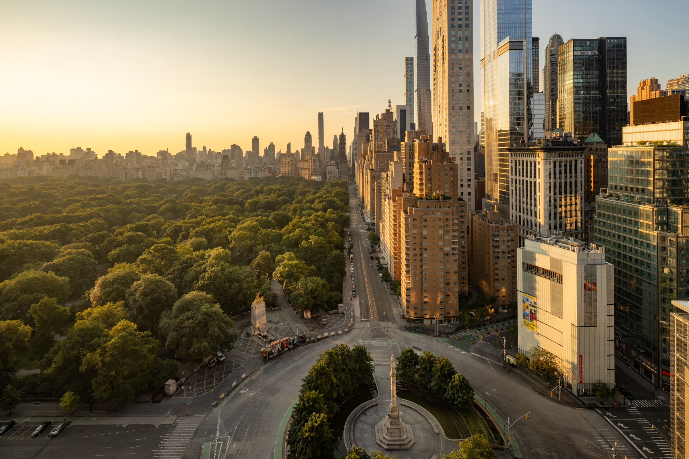 Skyscrapers and the trees of Central Park in New York with a road leading away from a large roundabout