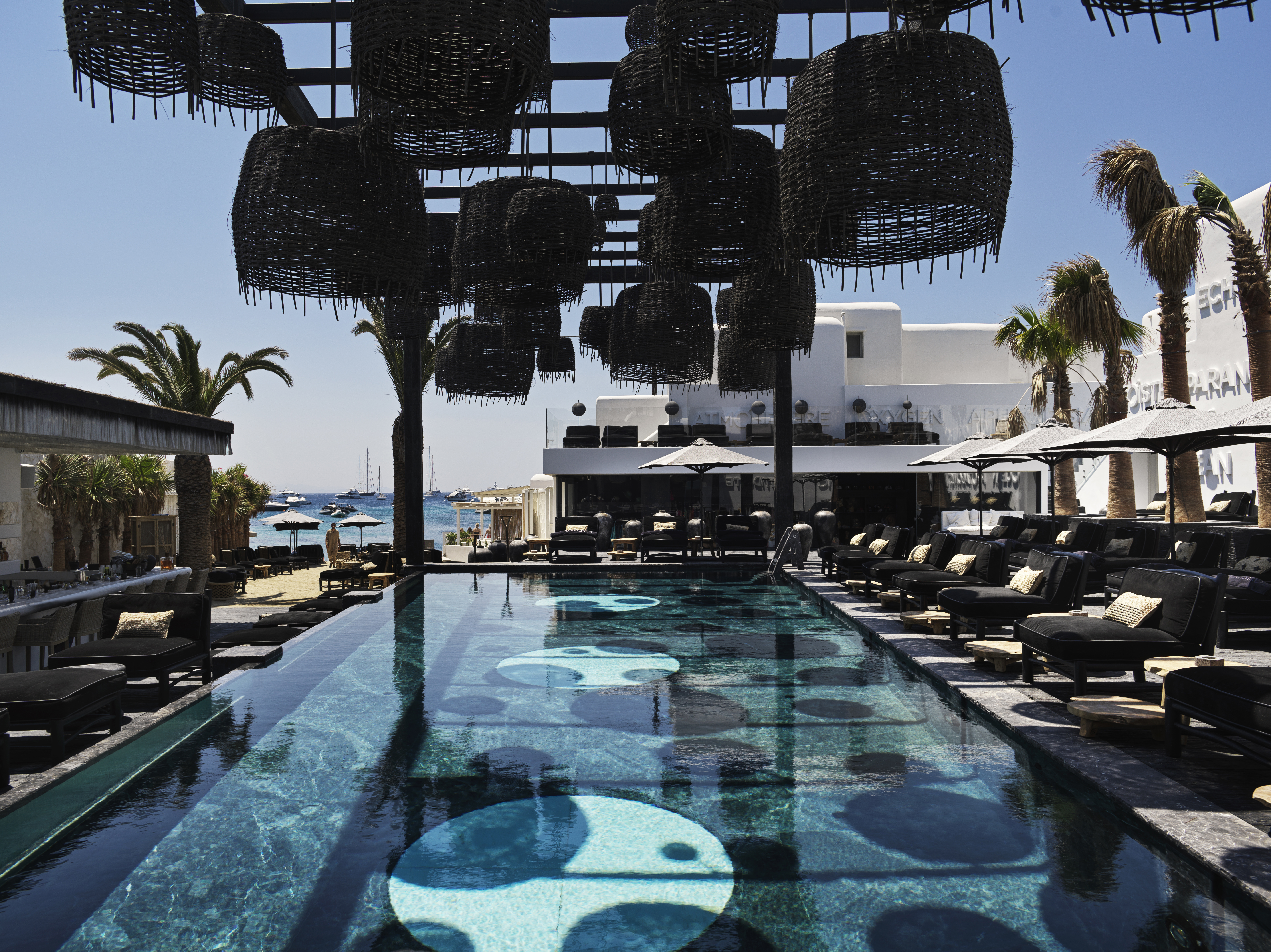 Main pool with black rattan furniture and loungers looking out to sea at Myconian O