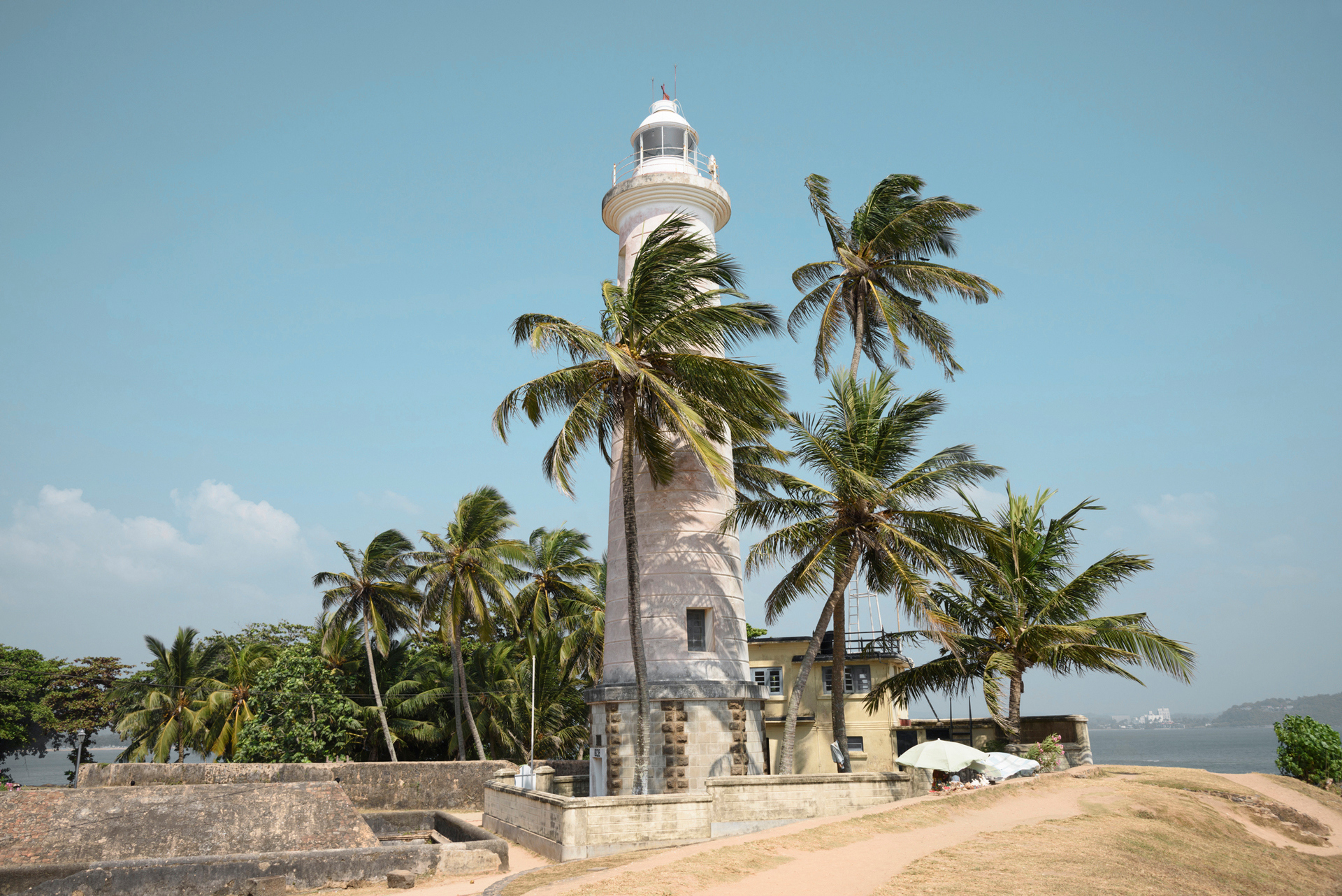 A white lighthouse surrounded by palm trees in Sri Lanka during the day