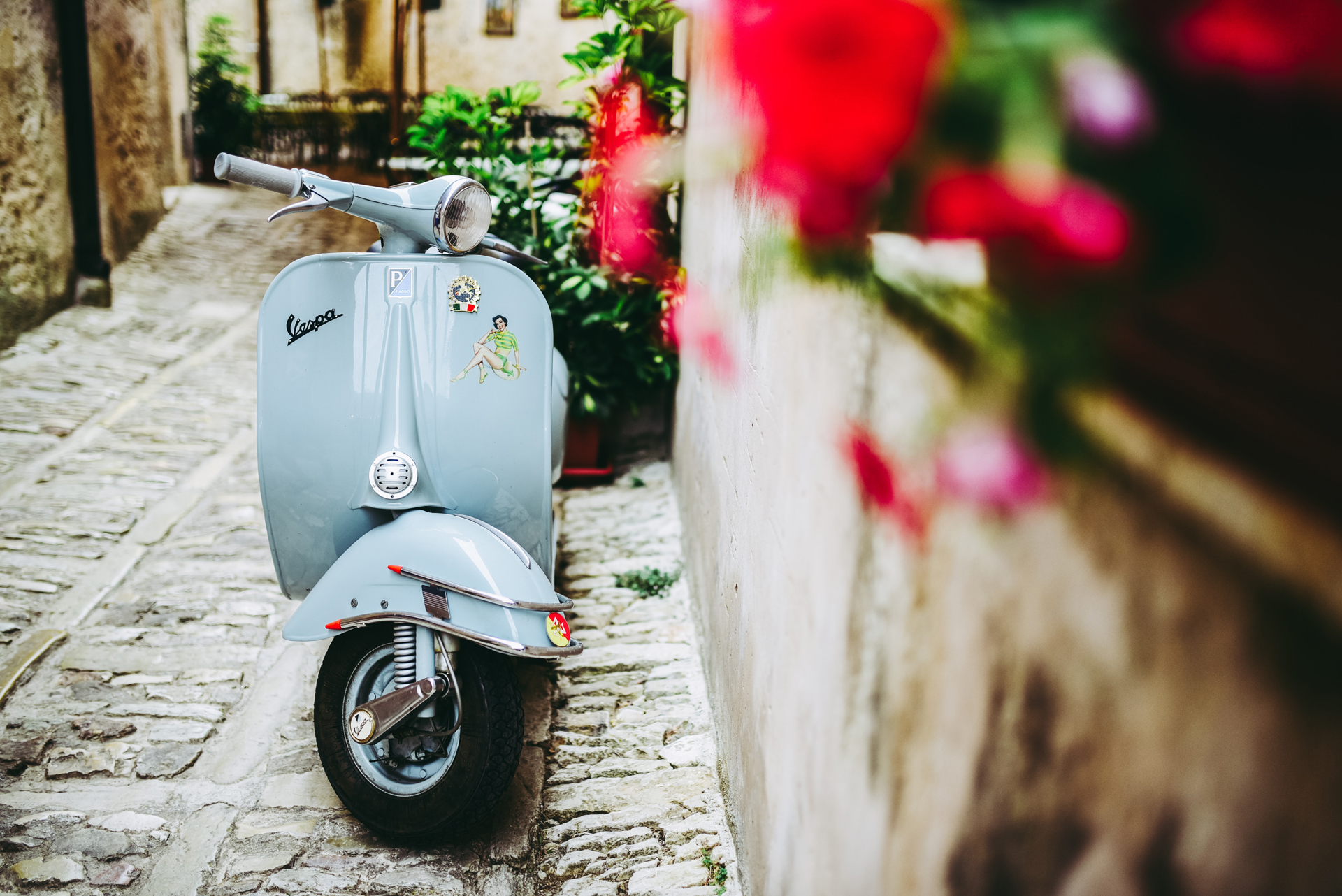 A blue scooter beside a concrete wall in Italy