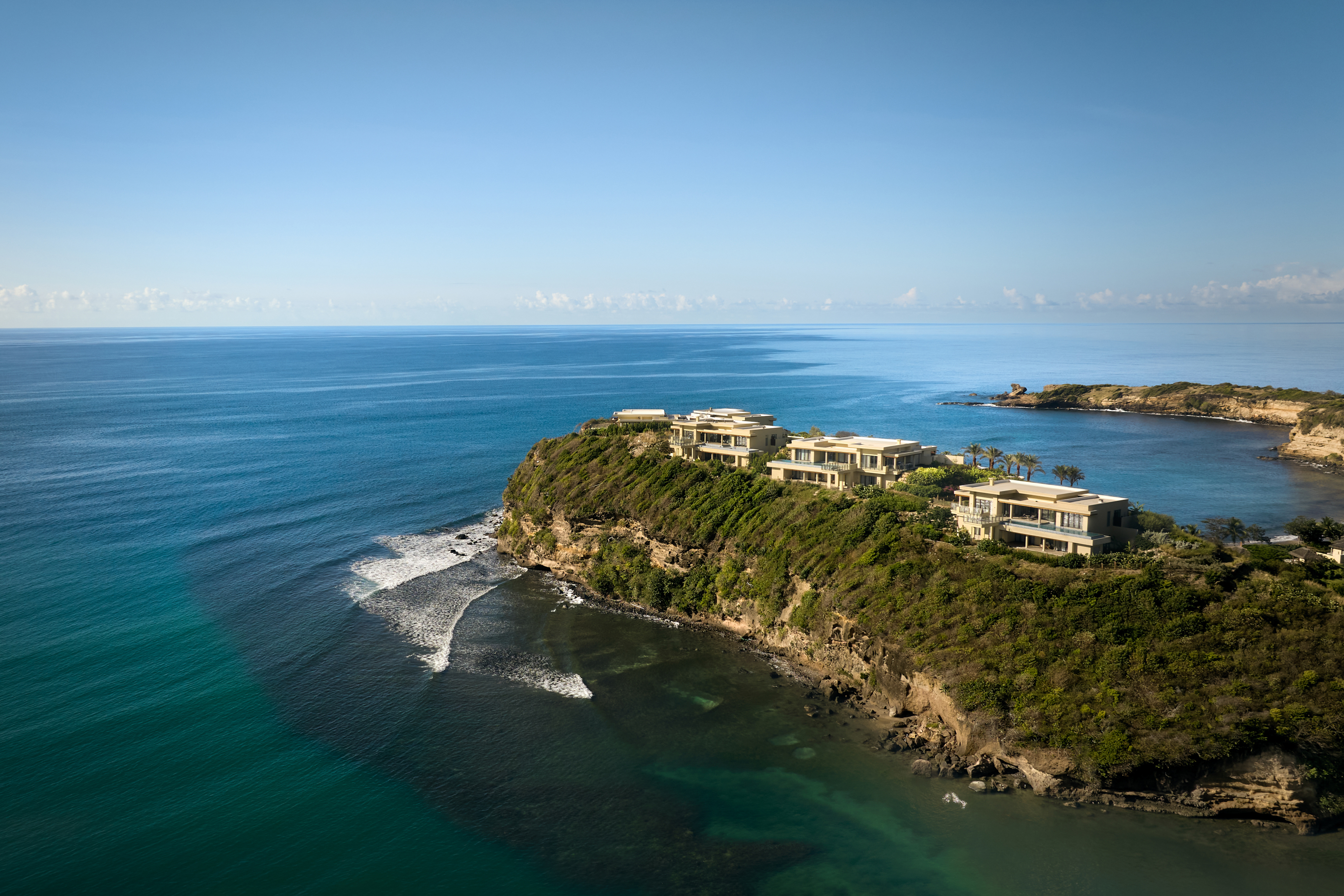 Five luxury villas sit on a green headland in Grenada, flanked by blue seas
