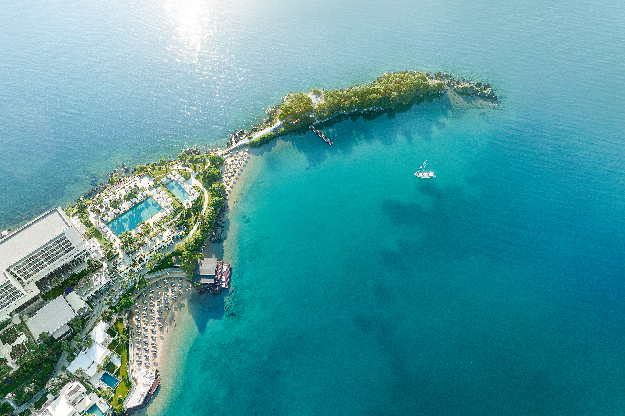 Aerial view of Grecotel Corfu Imperial resort with beachfront, luxury hotel, and turquoise Ionian Sea.
