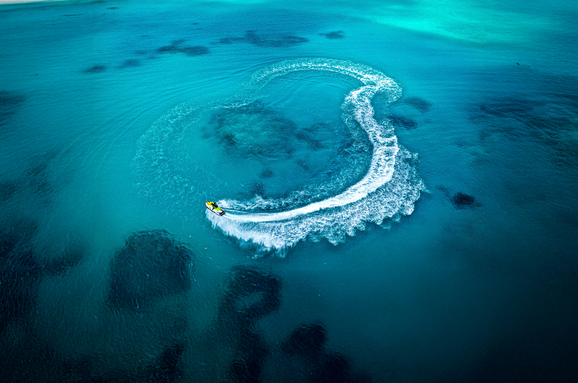 Speedboat travelling in a circle in the ocean, creating waves in its wake