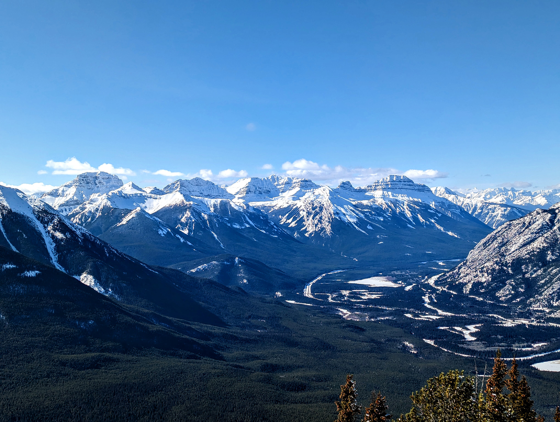 A view of a mountain range with snow capped mountains in the background