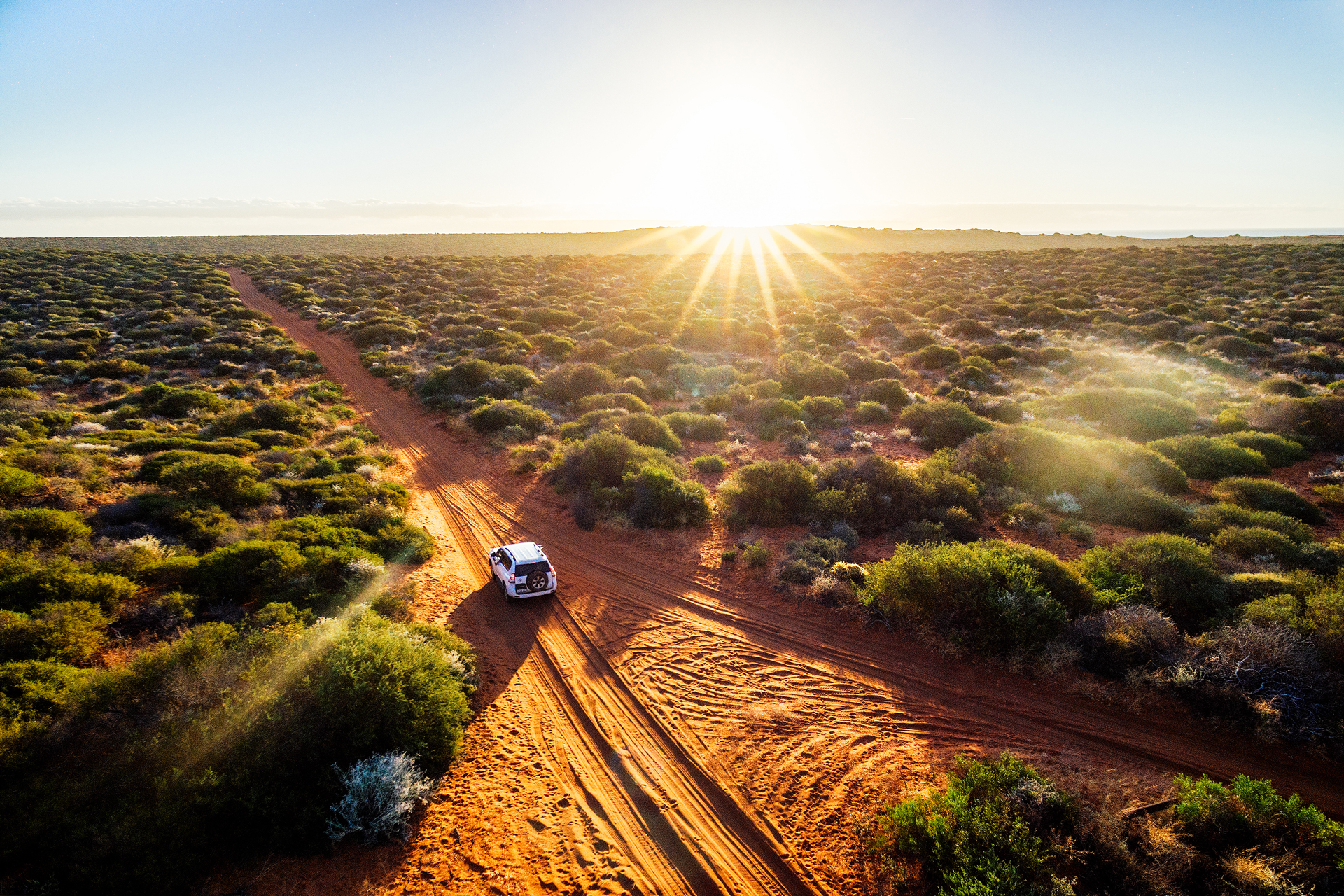 A white SUV driving on a dirt path in the Australian outback