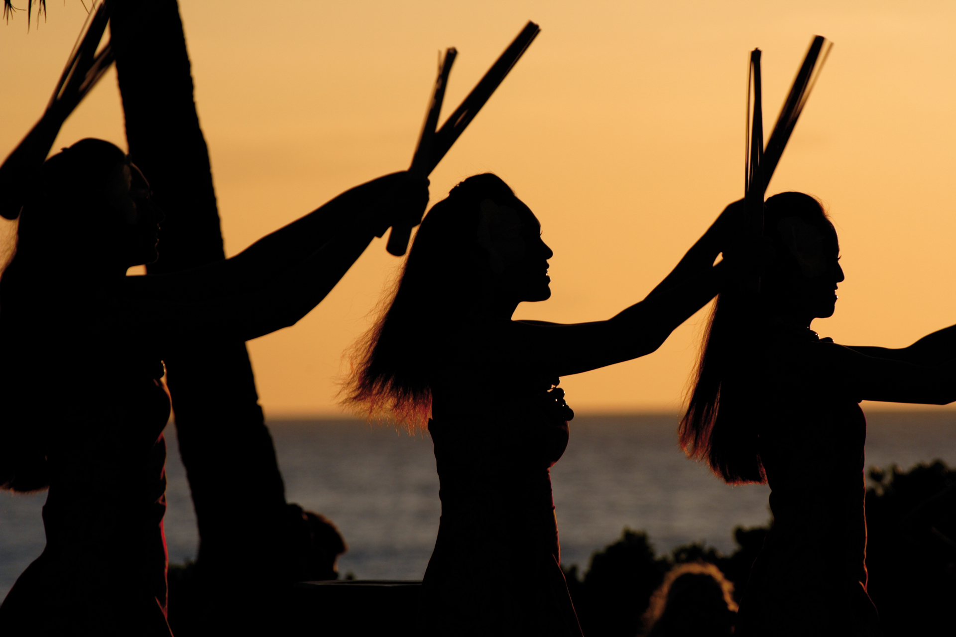 Luau dancers against a sunset sky on Oahu