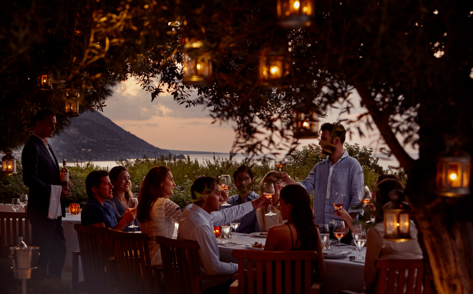 A big group of people toasting a drink in an outdoor dining area
