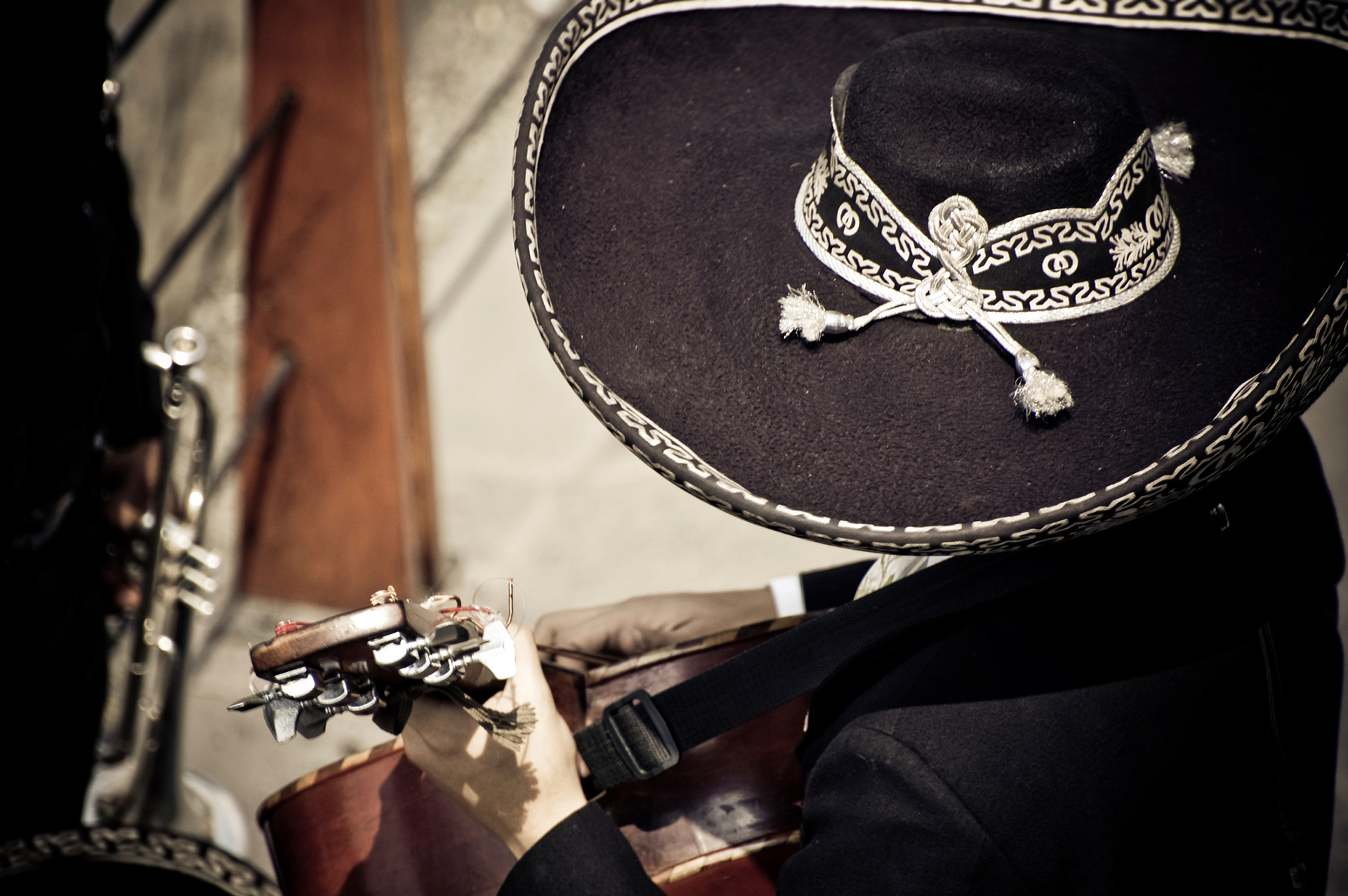 Mariachi man dressed in black playing a guitar