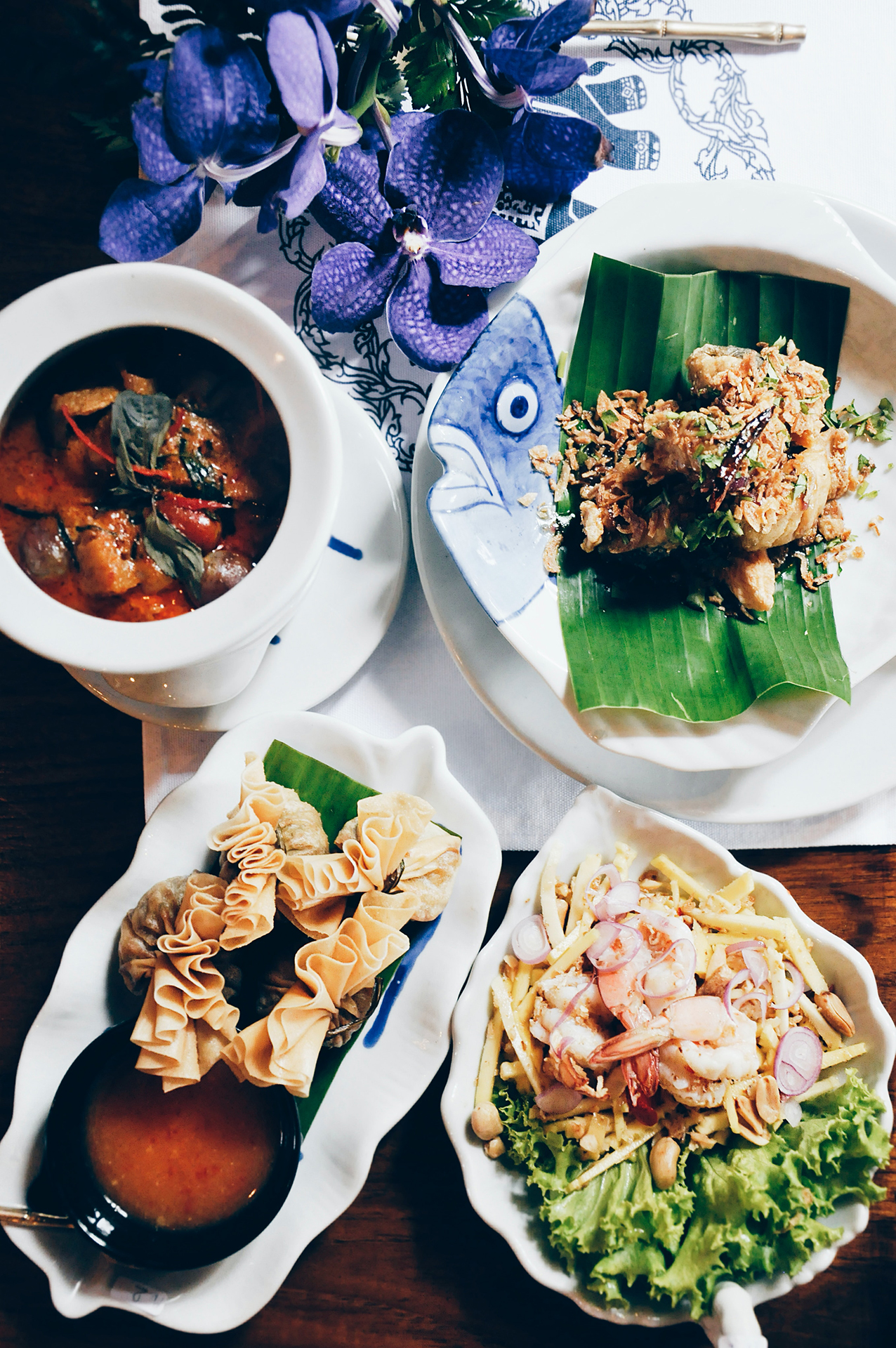 An array of food on white ceramic plates, one with a blue fish face design,
