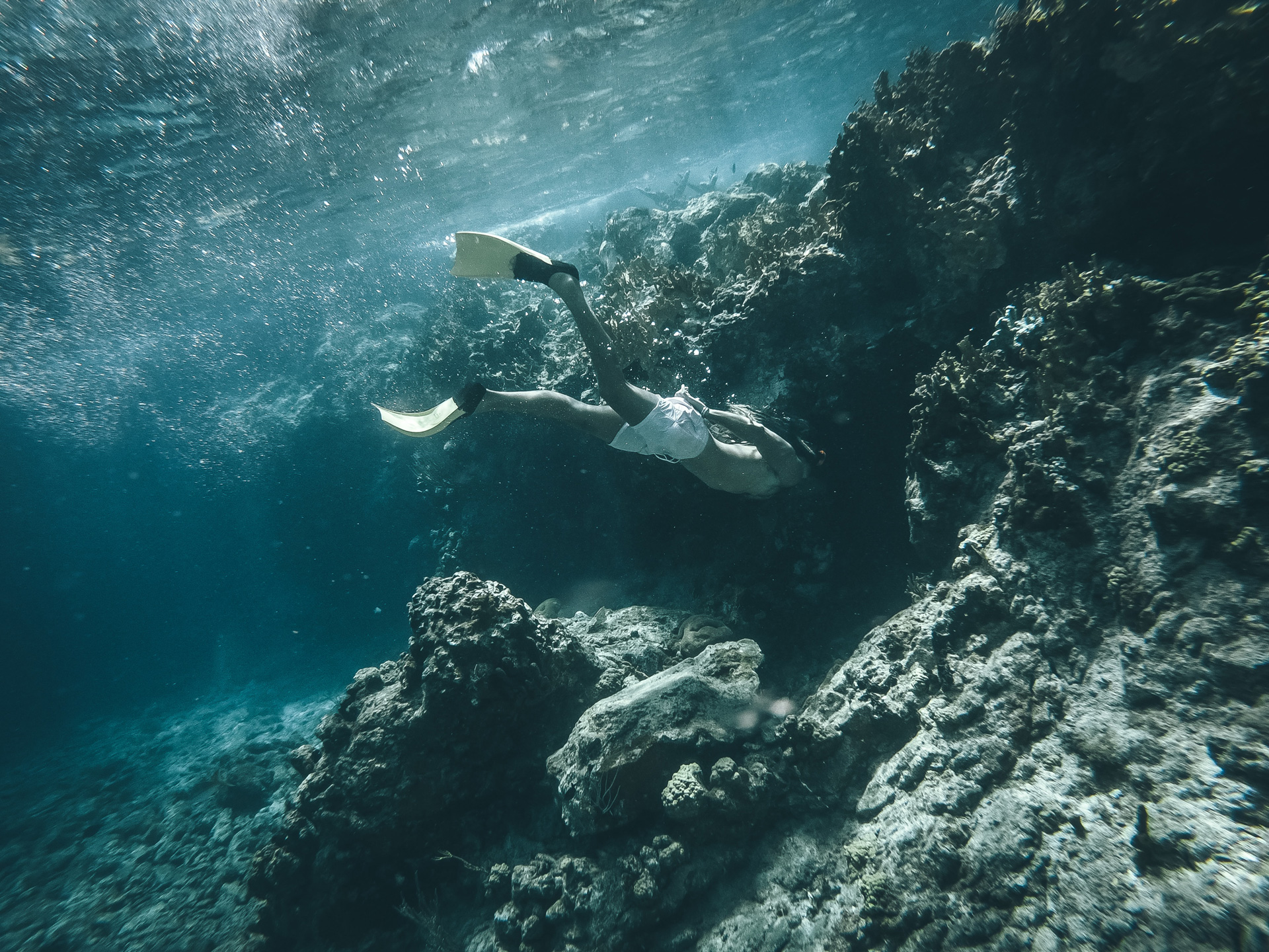 A man snorkeling looking into a small underwater cave