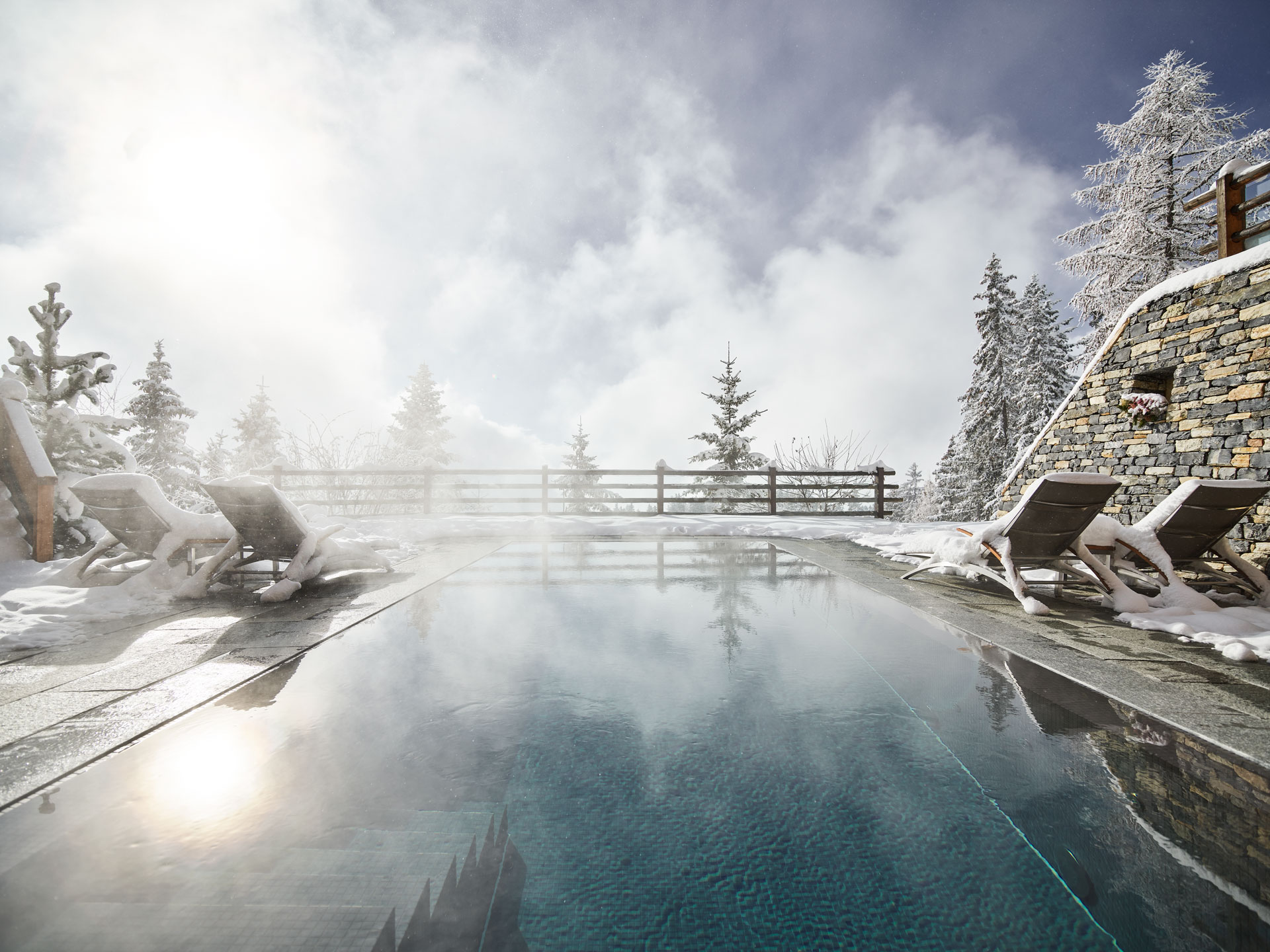 A steamy resort pools with loungers which are covered in snow