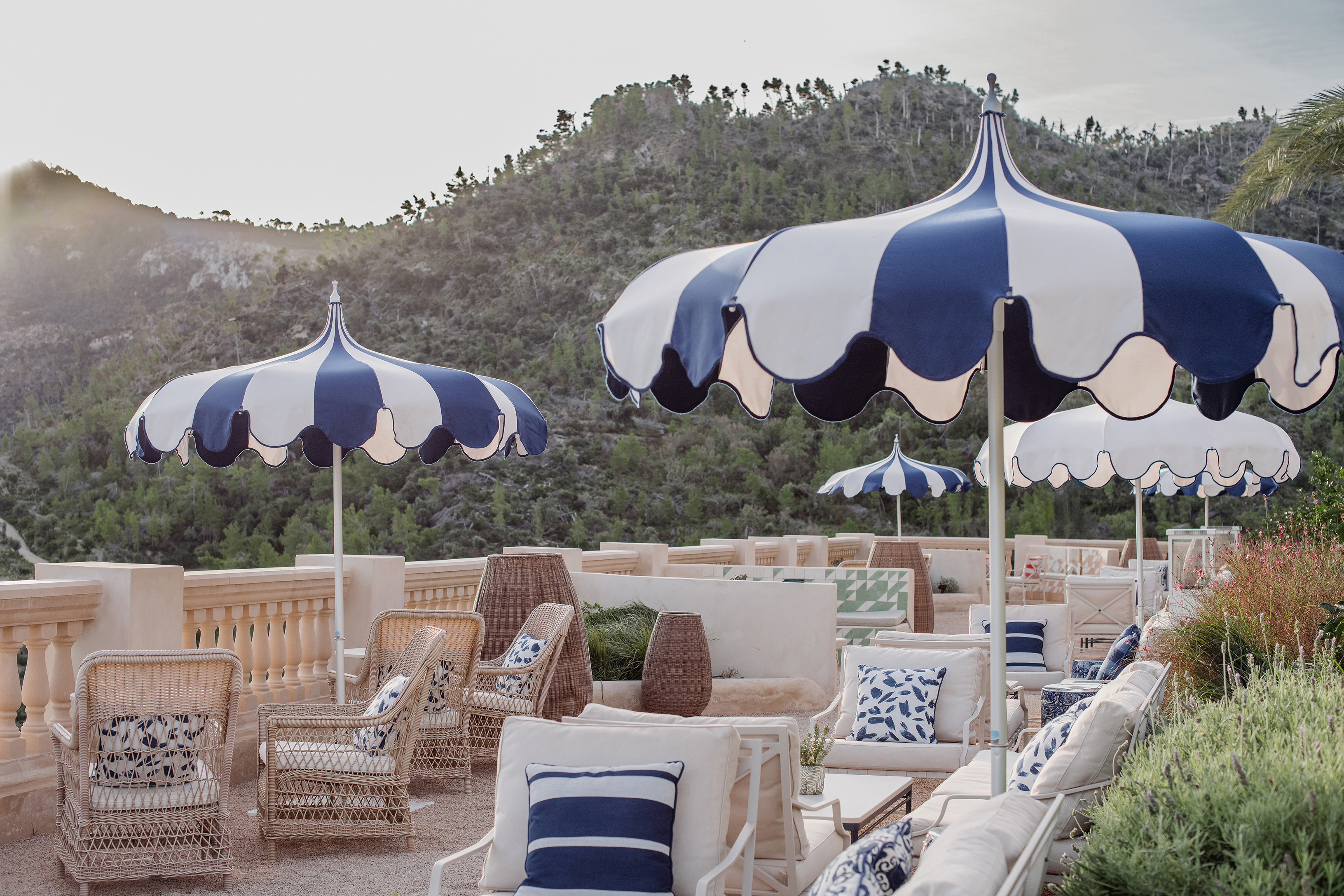 Main terrace loungers with blue and white umbrellas and mountains in the background