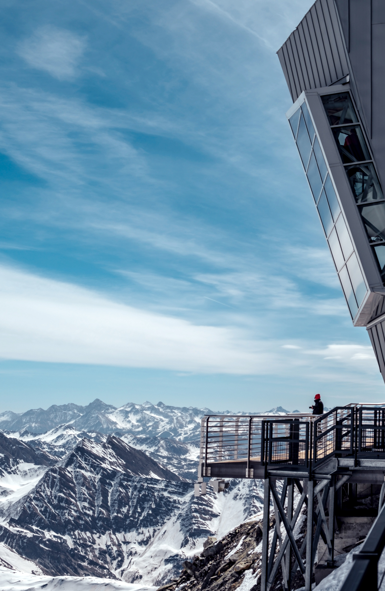 A person standing on a ski lift viewing platform looking out to the mountains