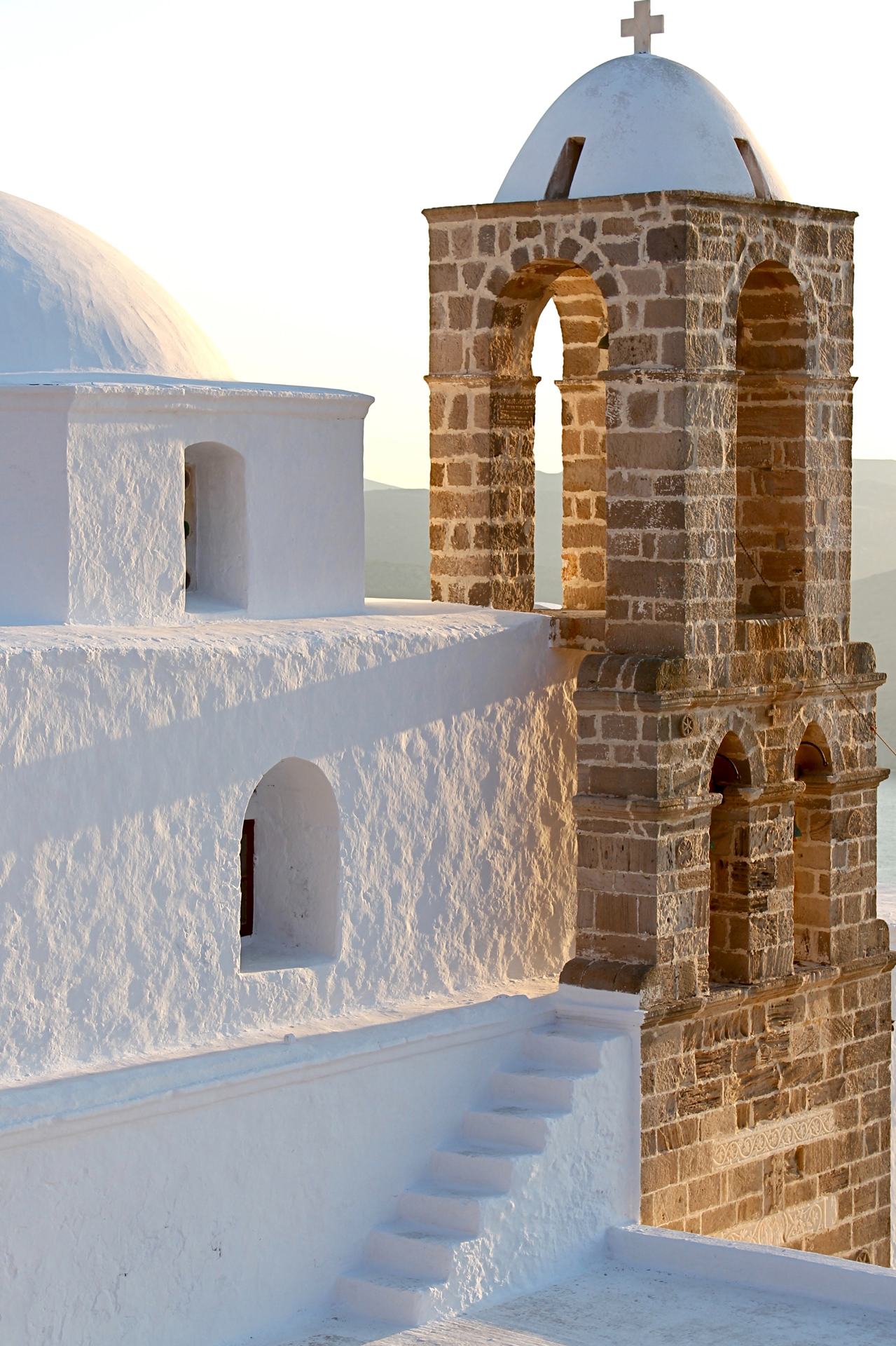 A white building next to a brick church tower