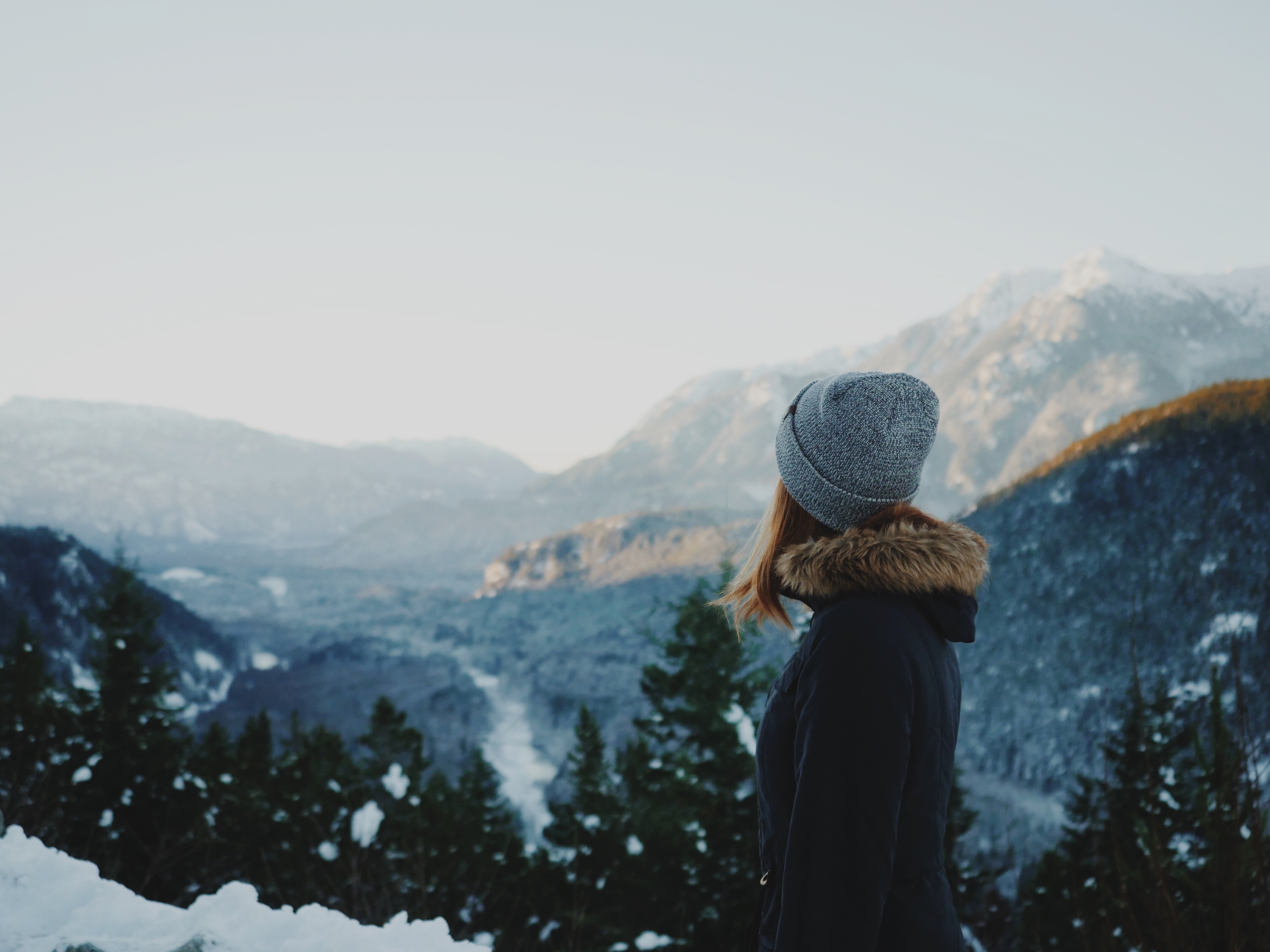 A woman wearing a grey beanie hat looking towards out of focus mountains