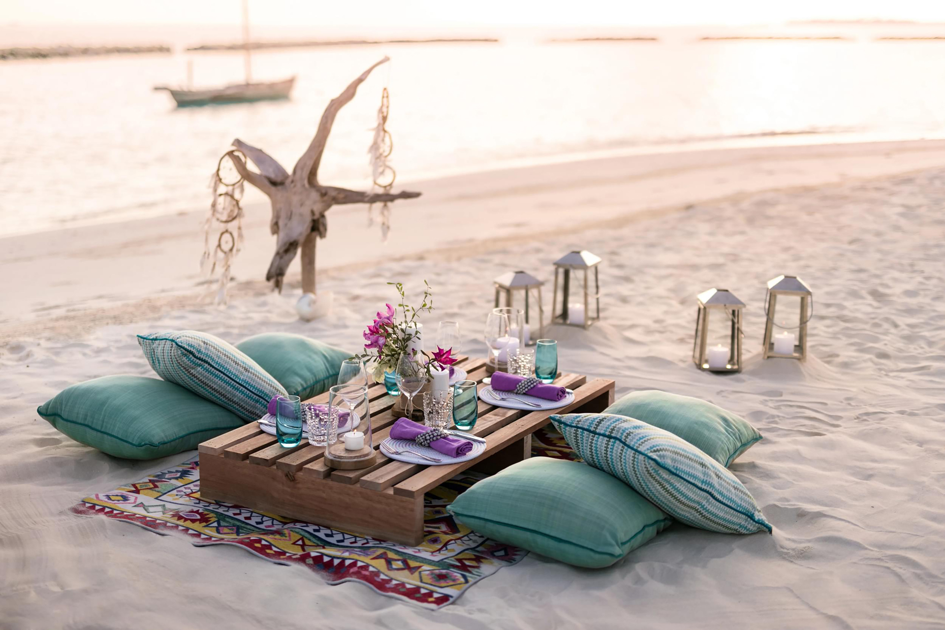 Picnic set up on the beach with cushions and candles