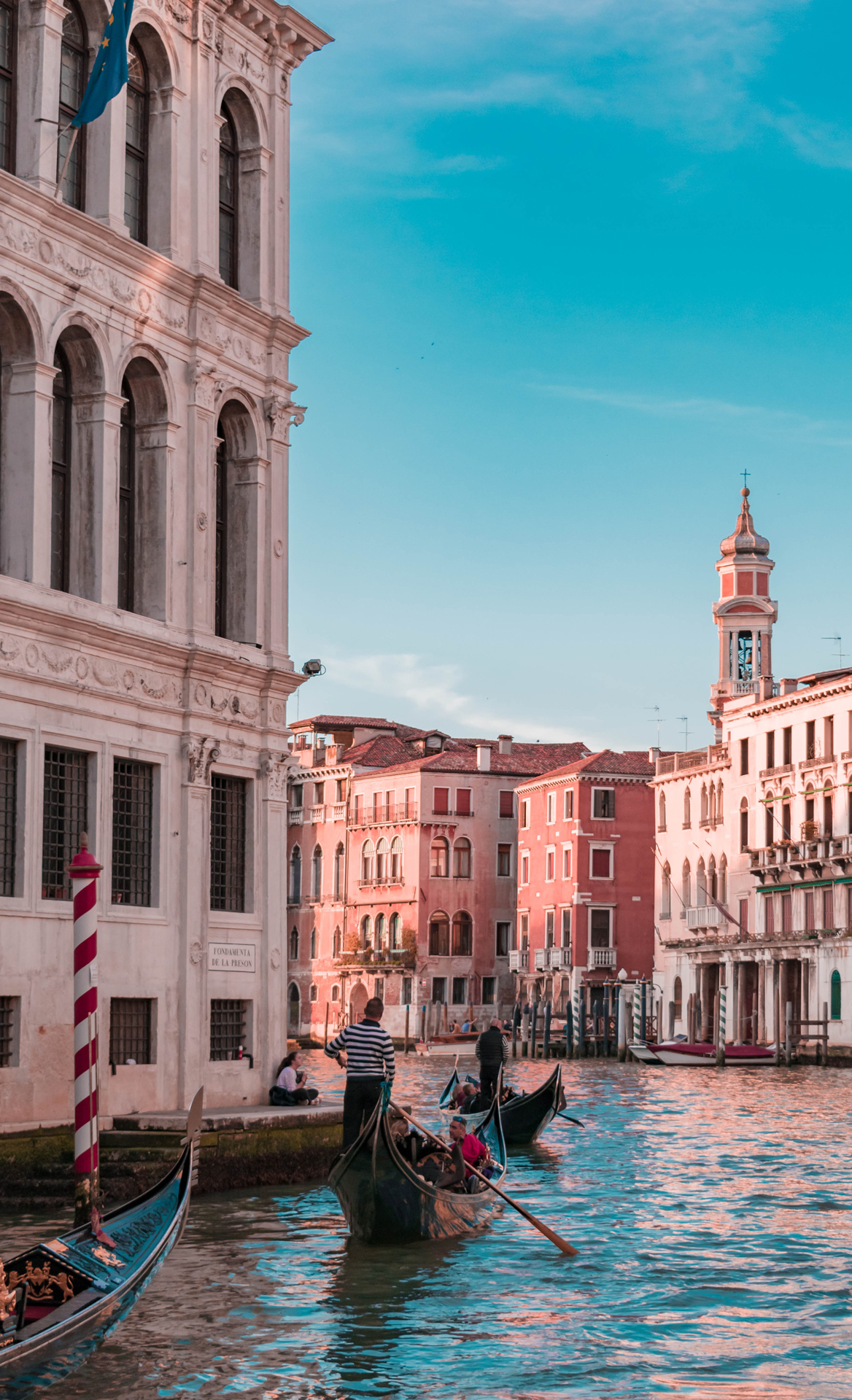 Gondola boats with people in on a canal between buildings in Venice
