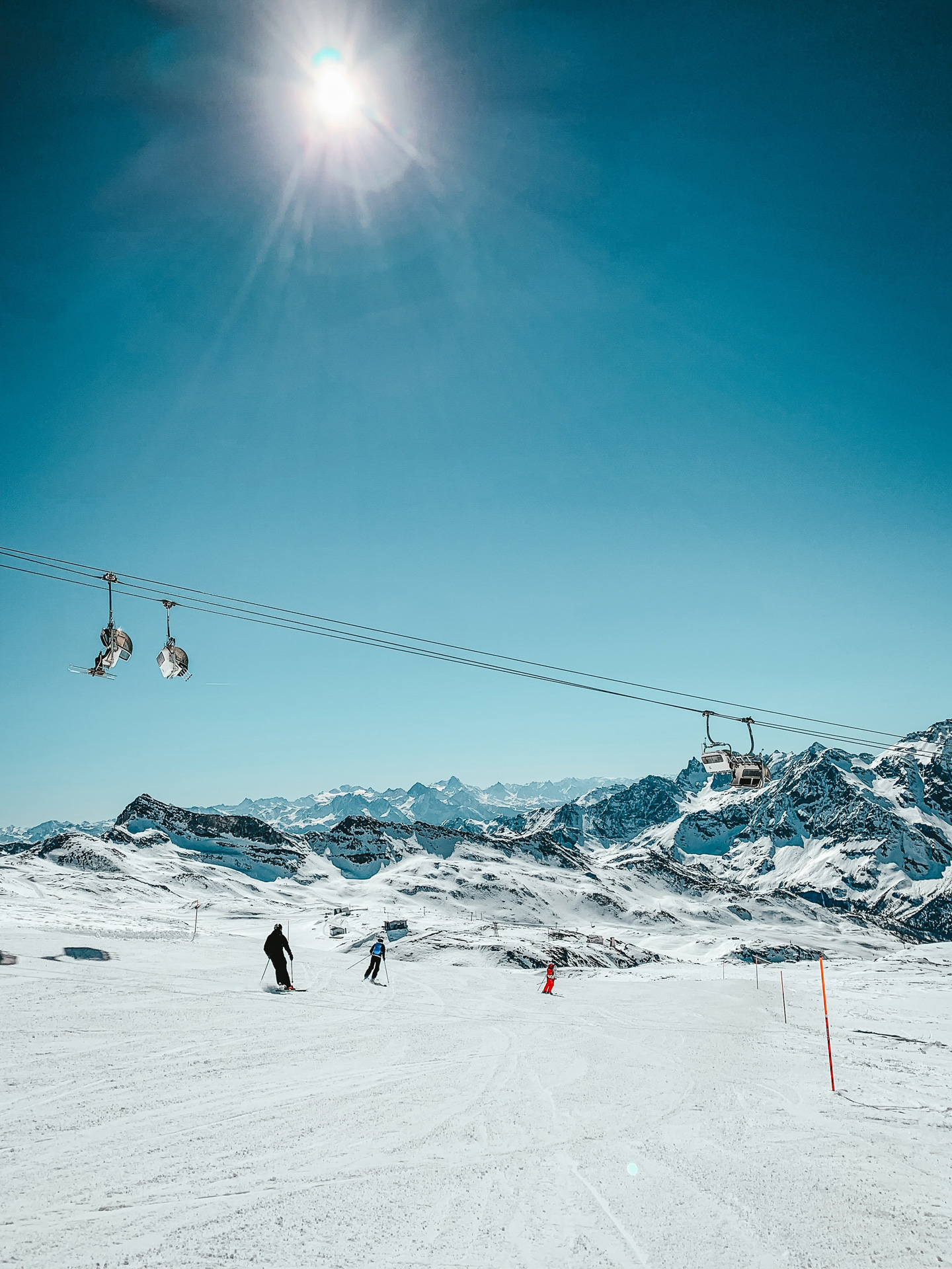 People skiing on snow-covered hill as ski lifts pass overhead